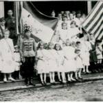 YMCA 1922 Monaville, WV. Hungarian Flag Day. Lena Loslo is holding the flag. Helen Tarkany Piros is the 2nd girl to the right of the man in uniform (his name maybe Berti). On the right, the little boy wearing the Russian looking hat is John Haslam. Courtesy of Bob Piros. Monaville, WV YMCA Flag Day, 1922