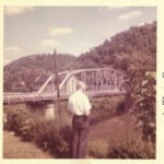 Photo courtesy of Mark Sefton. He writes. My Grandfather N.L. Sefton standing in the back yard overlooking the old bridge and YMCA. Peach Creek bridge and N. L. Sefton, Logan County, WV