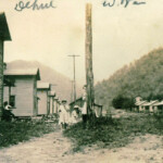 The picture was taken by Peter Flanigan during his work sinking the Dehue Mine vertical shaft and slope during 1917. He documented (in pictures and notations) the genesis or coming into being of Dehue. The family in the picture is the G. P. Harvey family. “G P” also worked on sinking the shaft and slope. His family included wife, Jane, and children Mary, Sicely, and Pauline. Another daughter, Dixie Adeline Harvey was born at Dehue on April 9, 1919. Following sinking the Dehue shaft and slope, “G P’ stayed on as a stone mason. Courtesy of Richard Fanigan. Dehue Camp 1917