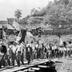Logan, WV union members marching onto the Island circa 1940s. Courtesy of UMWA. Ref. Image 19210134. Logan, WV union members marching