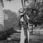 1949 yard of the Bush home at Cherry Tree courtesy of Bob Piros. Anna Tarkany holding Bob Piros in the tree. A cherry tree is in the background. (Cherry Tree BP48941) 1949 yard of the Bush home at Cherry Tree, Logan County, WV